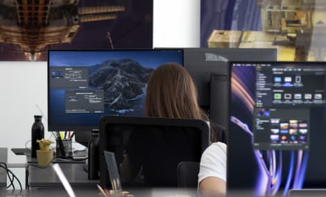 People working in front of multiple screen inside Notomia's office